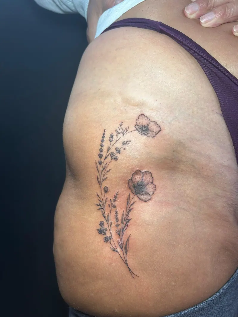 Fineline-Tattoo eines Wildblumenzweigs mit Lavendel an der Hüfte, gestochen von Cindy