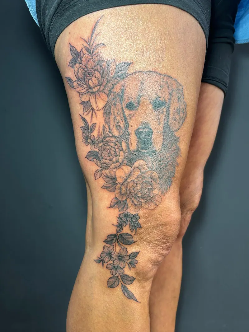Black-&-Grey-Tattoo eines Hundeportraits mit Rosen und Blütenranke am Oberschenkel, gestochen von Cindy