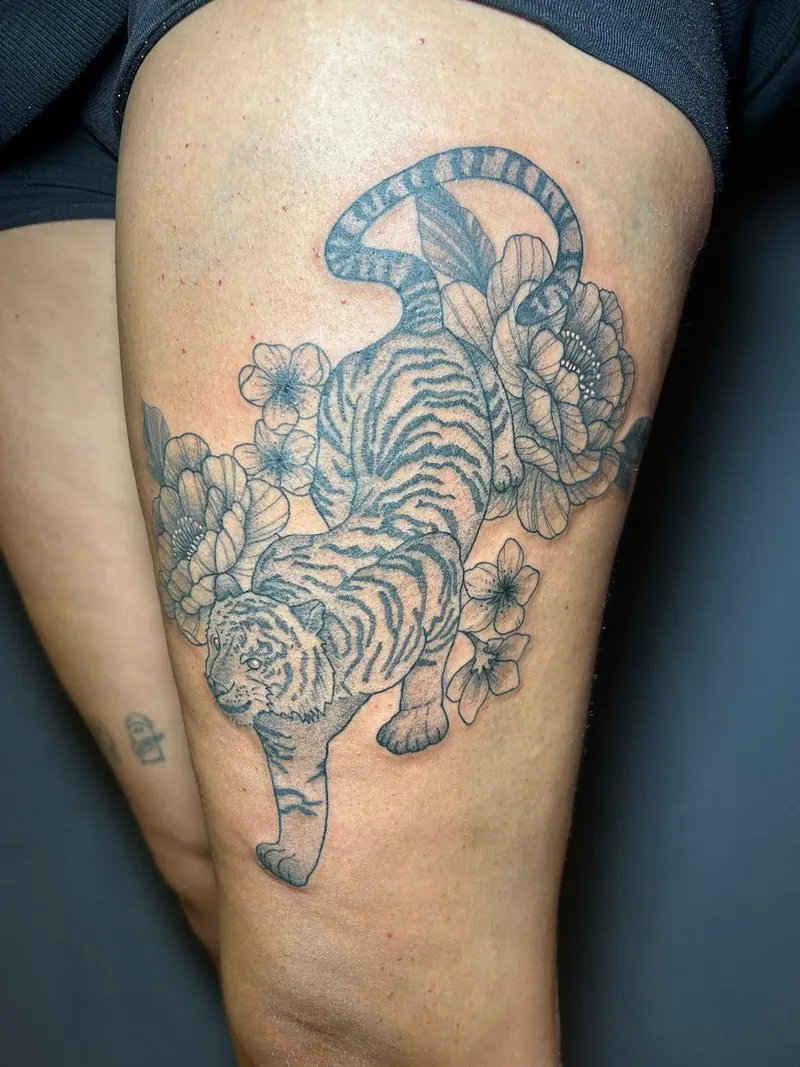 Fineline-Tattoo eines schleichenden Tigers zwischen Pfingstrosen am Oberschenkel, gestochen von Cindy