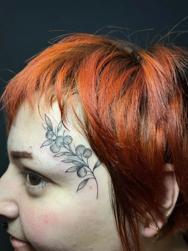 Fineline-Tattoo eines Zweigs mit Beeren an der Schläfe, gestochen von Cindy