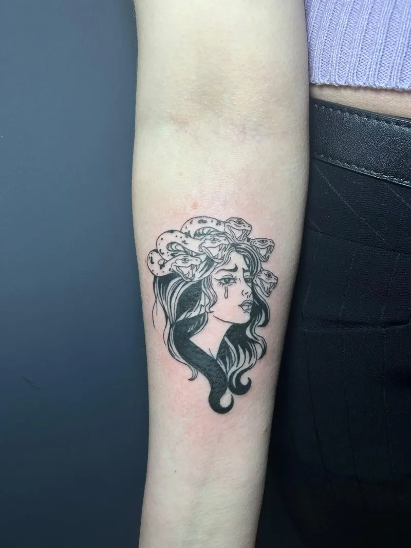 Blackwork-Tattoo eines Medusa-Kopfs mit Schlangenhaar am Unterarm, gestochen von Cindy