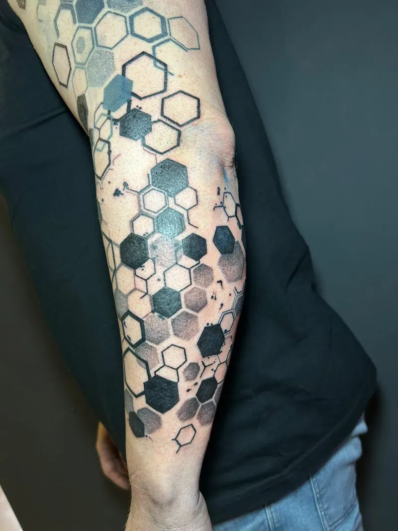 Geometrisches Tattoo eines Wabenmusters aus Sechsecken am Unterarm, gestochen von Cindy