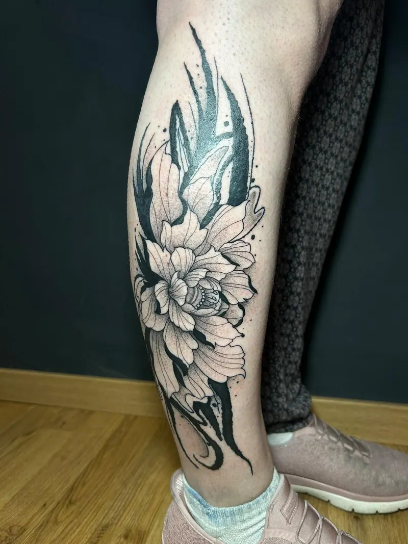 Tattoo einer großen Blüte mit kräftigen Blackwork-Flächen an der Wade, gestochen von Cindy