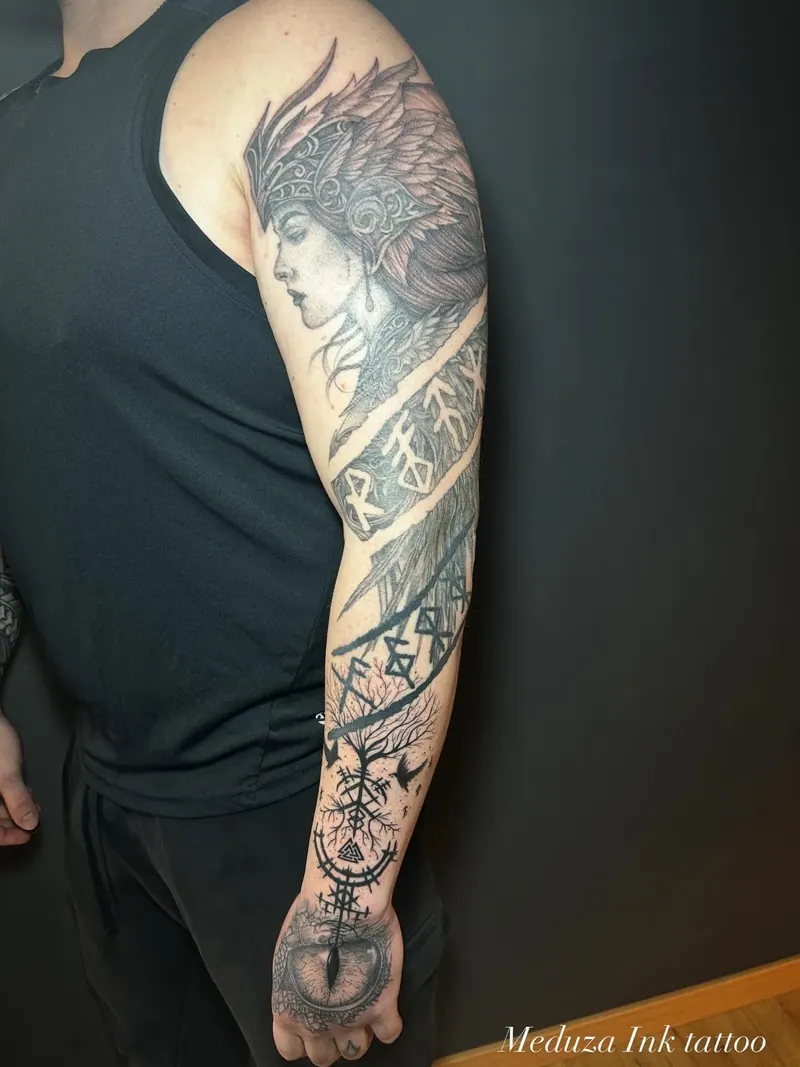 Black-&-Grey-Armtattoo einer Kriegerin mit Federkopfschmuck, Runenbändern und Auge auf dem Handrücken, gestochen von Cindy
