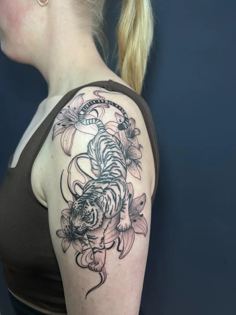 Tattoo eines Tigers mit Lilien an Schulter und Oberarm, gestochen von Cindy