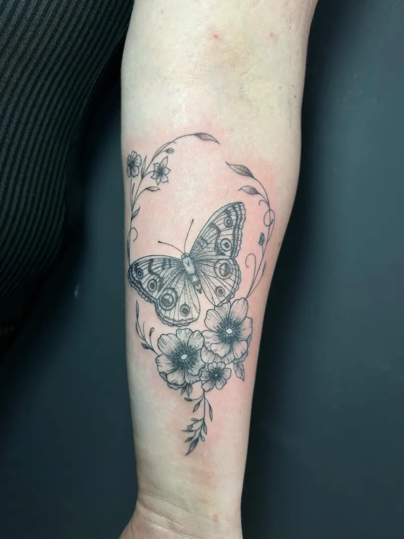 Fineline-Tattoo eines Schmetterlings mit Blüten am Unterarm, gestochen von Cindy