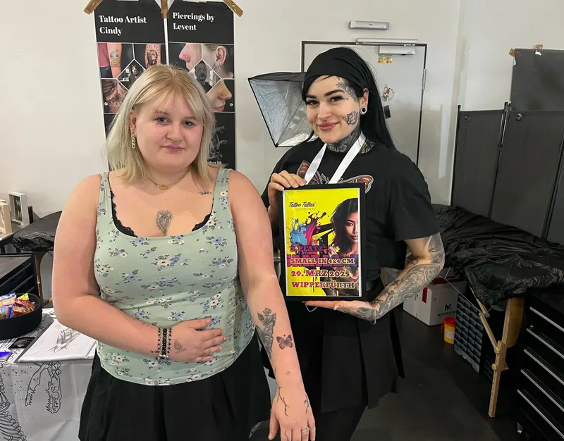 Cindy mit Kundin und Urkunde bei einer Siegerehrung auf einer Tattoo-Convention