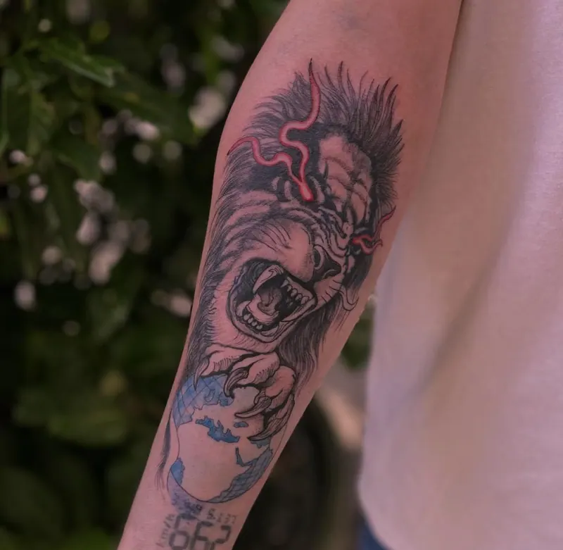 Black-&-Grey-Tattoo eines brüllenden Gorillas mit Weltkugel und roten Akzenten am Unterarm, gestochen von Paul