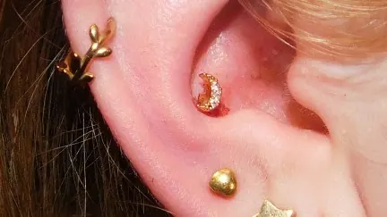 Helix- und Conch-Piercing mit goldenem Schmuck (Zweig und Halbmond), gestochen von Levent