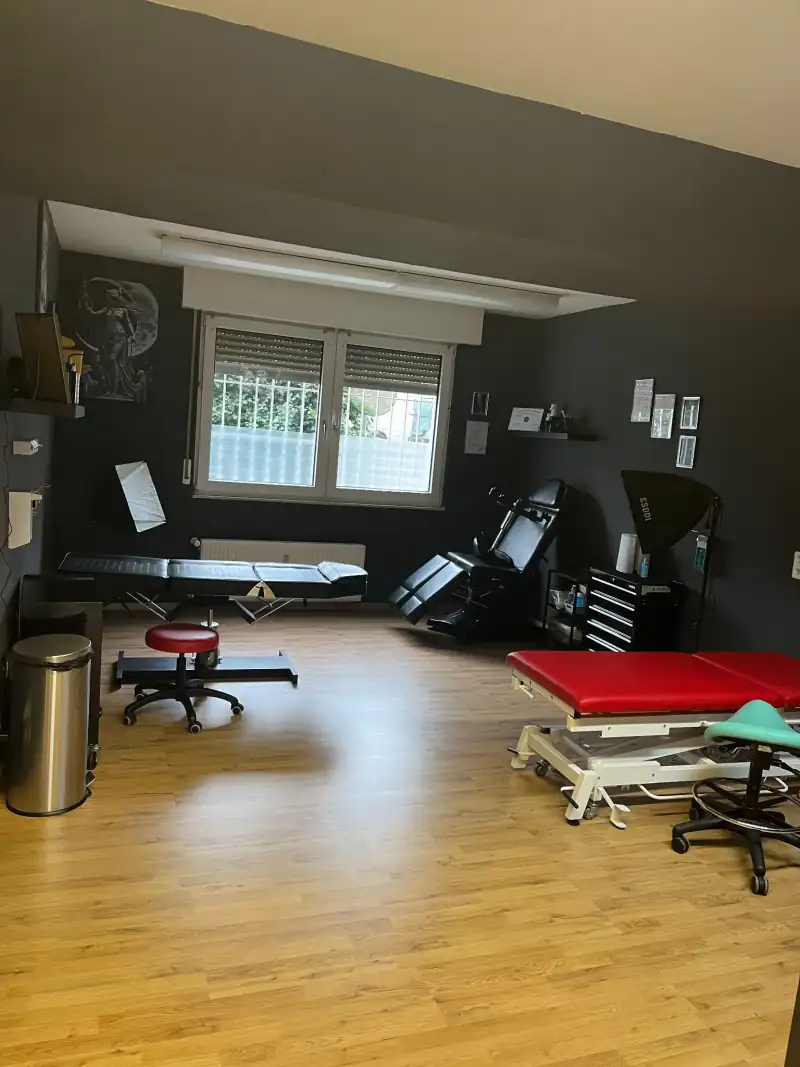 Arbeitsbereich im Studio mit Liegen, Tattoo-Stuhl und Holzboden