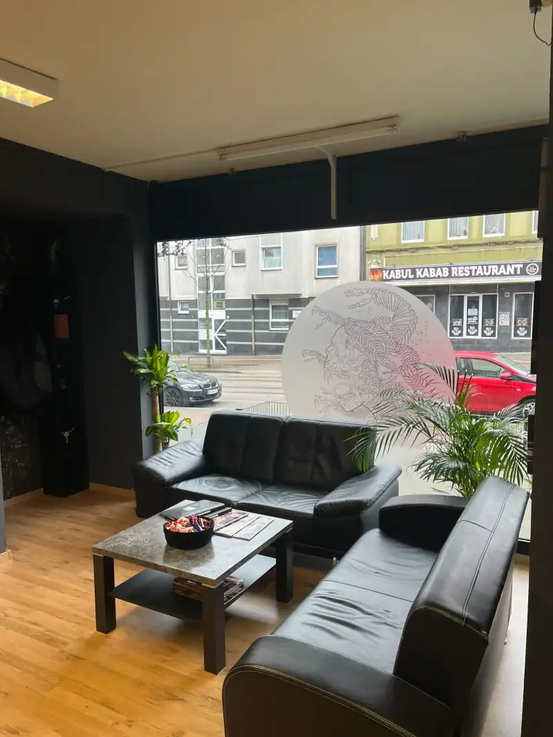 Wartebereich mit schwarzen Ledersofas vor der großen Fensterfront