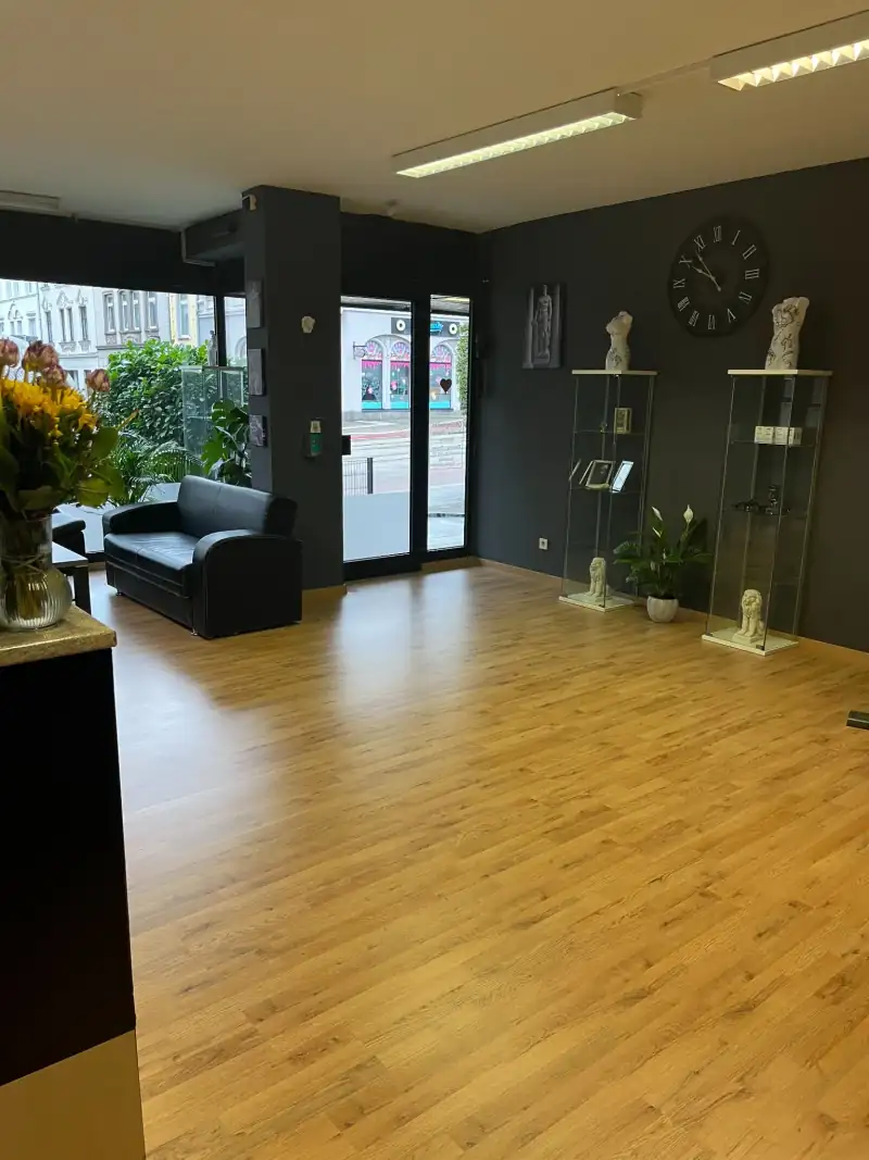 Heller Eingangsbereich mit Sofa, Vitrinen und Wanduhr