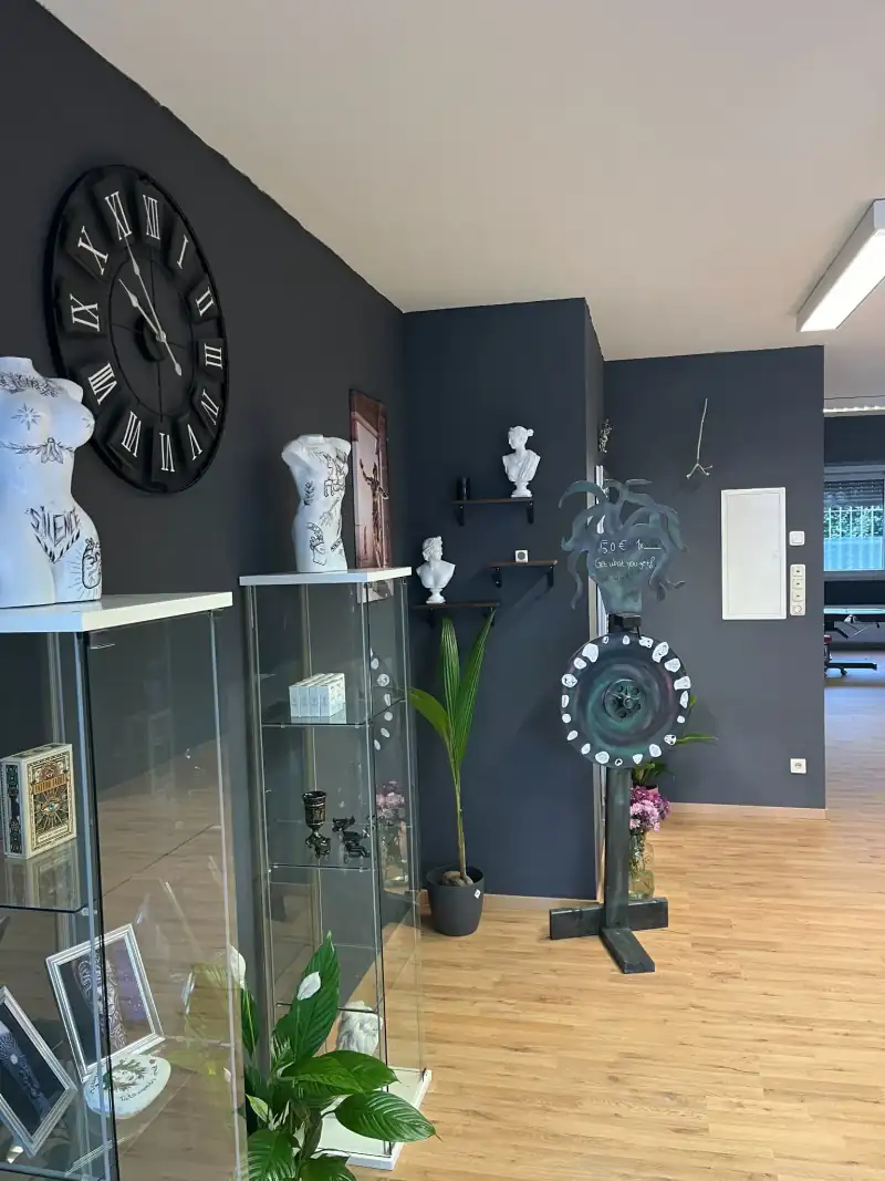 Vitrinen mit Schmuck und Deko-Figuren vor dunkler Wand mit großer Wanduhr